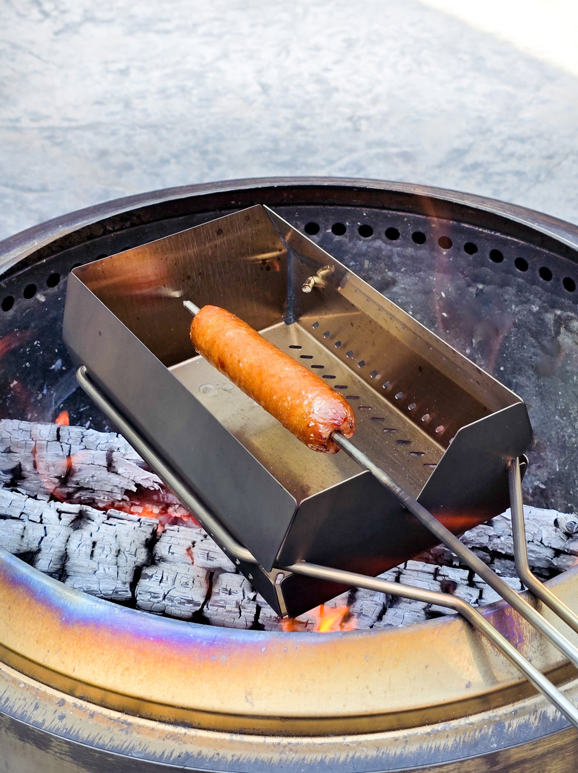 A hot dog being roasted on the skewer over a bonfire. Perfect for any family occasion and making the best hot dogs.